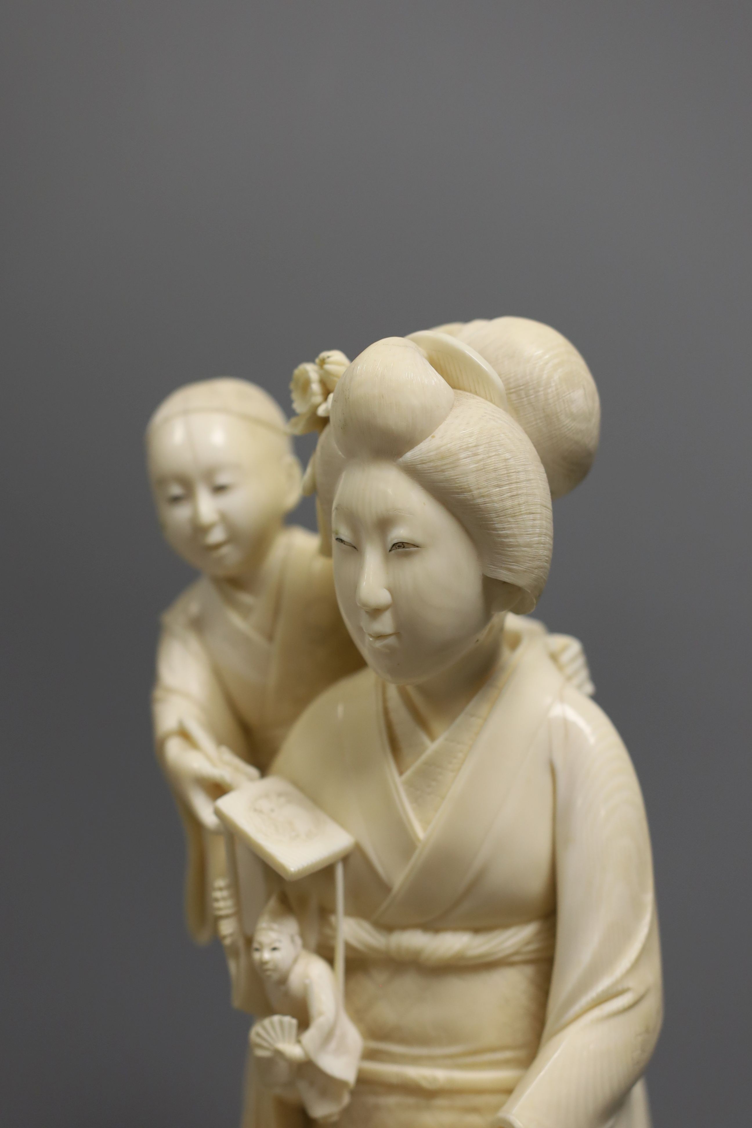 A large Japanese Tokyo School ivory okimono of a lady with child holding a puppet, Meiji period, 31 cms high.